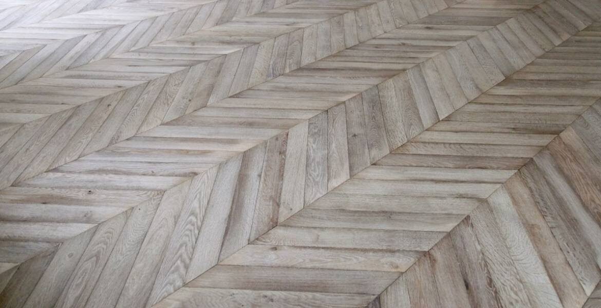 Close-up of herringbone patterned hardwood flooring in a light natural finish