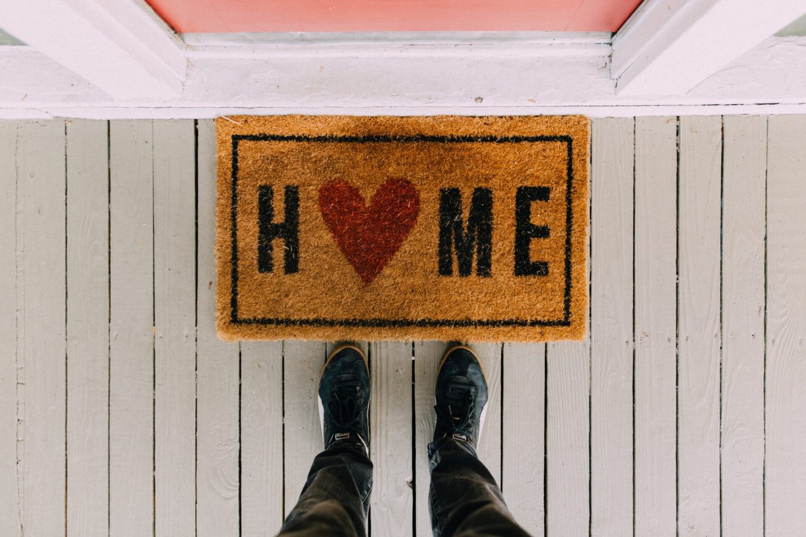 Welcome mat with the word "HOME" and two feet standing on a striped porch