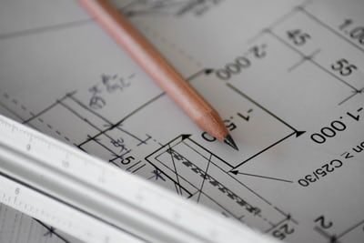 Person's hand drawing on a home floorplan with a pen, planning lighting layout