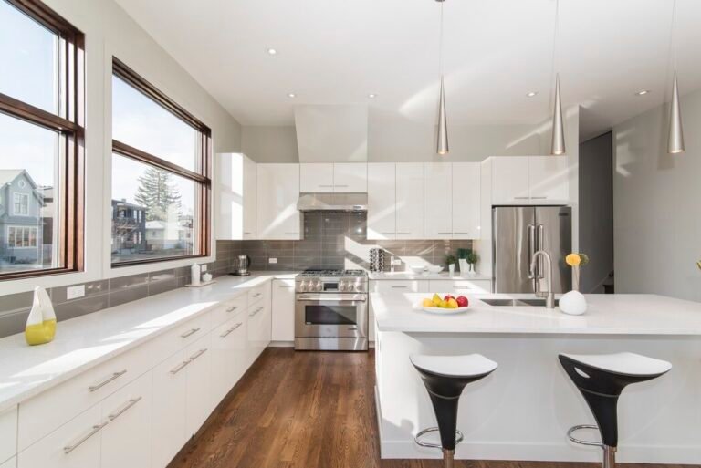 Modern kitchen with white cabinets, stainless steel appliances, and a bowl of fruit on the counter