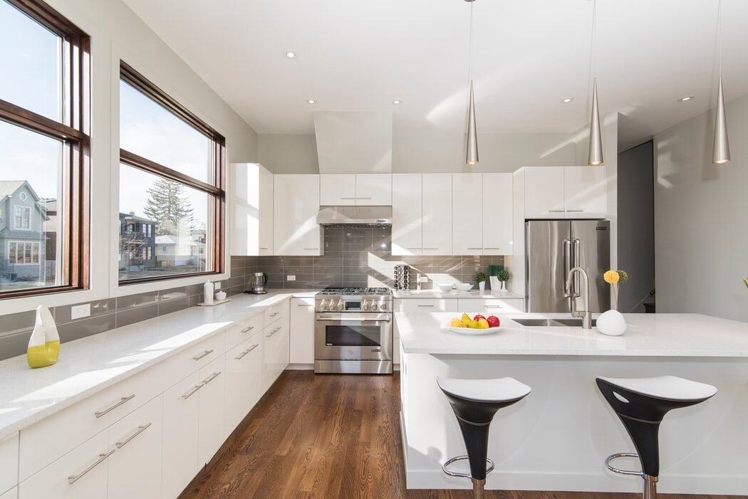 Modern kitchen with white cabinets, stainless steel appliances, and a bowl of fruit on the counter