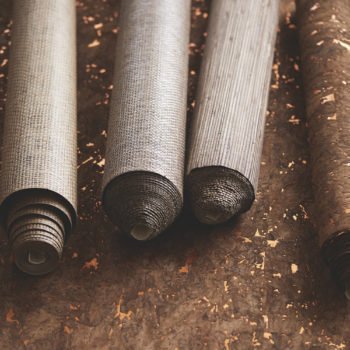 Close-up of rolled metallic wallpaper in shades of silver, bronze, and gold