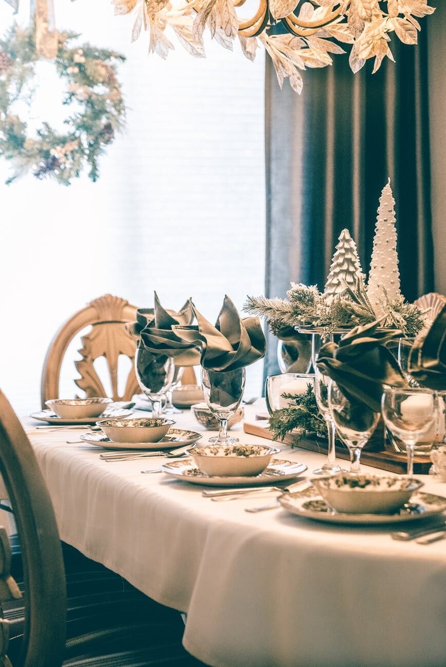 Dining table set for a holiday meal with gold decorations, folded napkins, and fine china