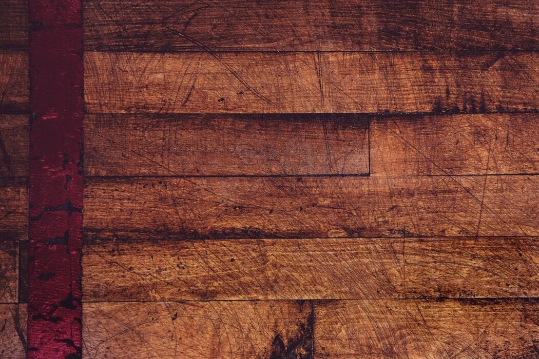 Close-up of old, worn hardwood floorboards with visible scratches and stains